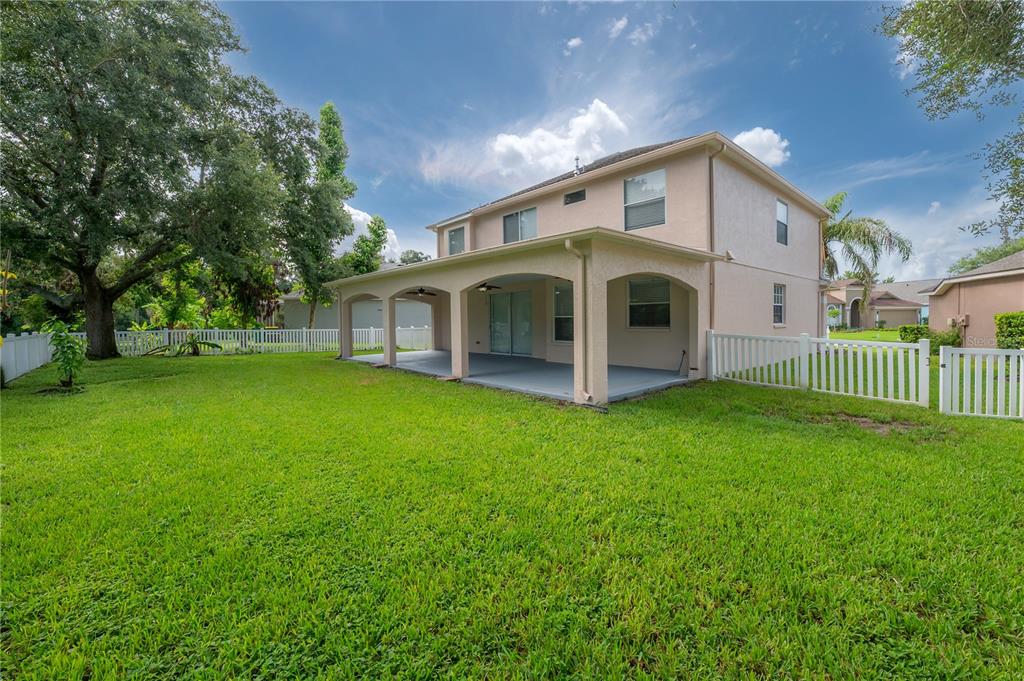 A two-story house with a covered back patio and a white vinyl fenced yard — 4716 MAPLETREE LOOP, WESLEY CHAPEL, FL