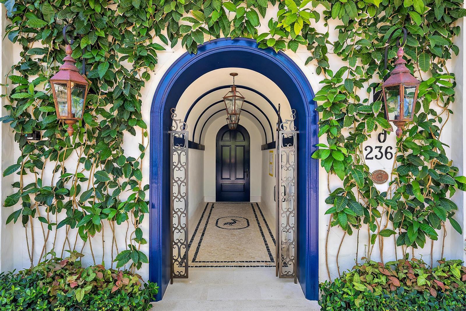An arched entryway with a blue frame, iron gates, and a tiled floor with vines — 236 Phipps Plaza # 101, Palm Beach FL 33480, PALM BEACH, FL