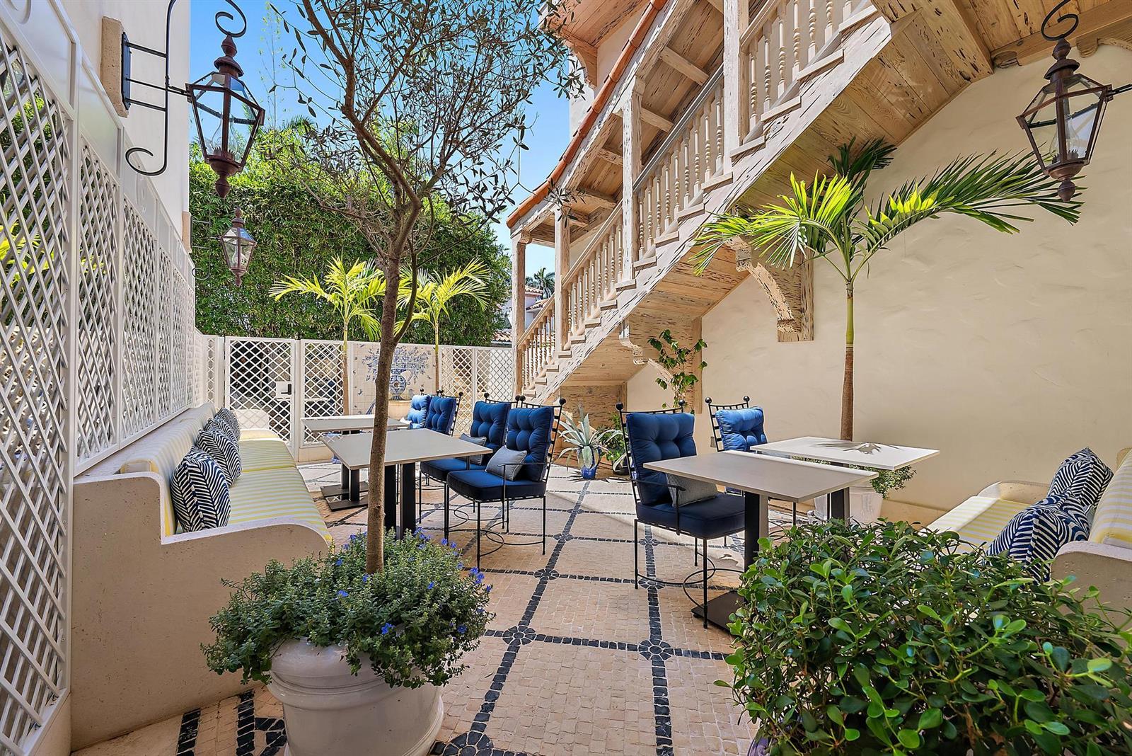 An outdoor patio features tables, blue chairs, built-in benches, and a wooden staircase — 236 Phipps Plaza # 101, Palm Beach FL 33480, PALM BEACH, FL