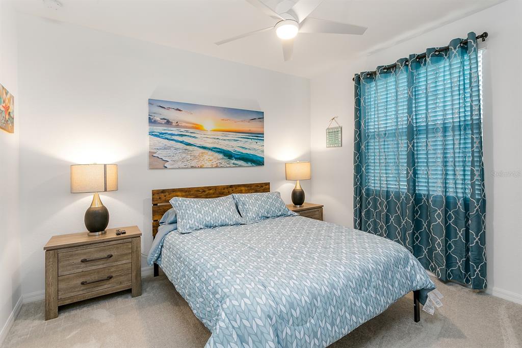 A bedroom features a bed with a patterned blue comforter, two nightstands, and blue curtains — 18028 GAWTHROP DRIVE UNIT 108, BRADENTON, FL