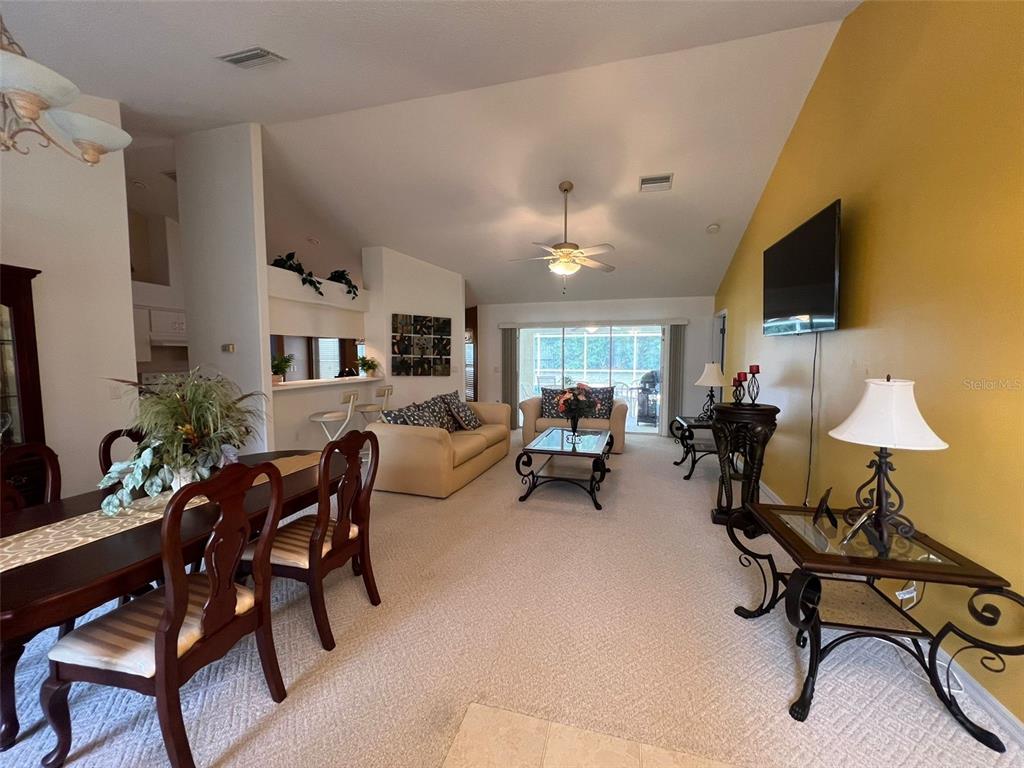 A dining area and living room with vaulted ceilings, carpeted floors, and a yellow accent wall — 9998 N LANGDON ROAD, CITRUS SPRINGS, FL