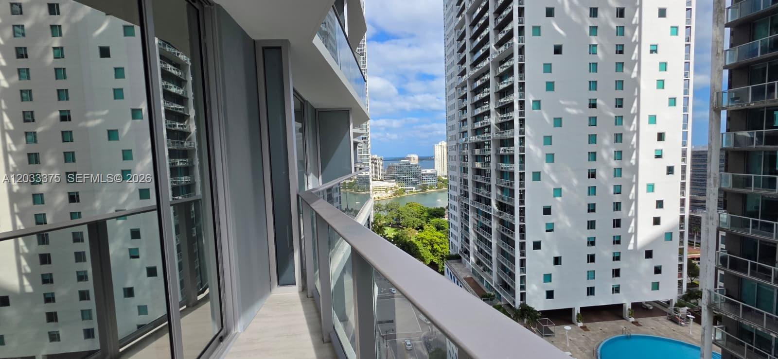 A balcony with a glass railing overlooks a swimming pool and nearby high-rise buildings — 77 SE 5th Street # 2108, Miami FL 33131, MIAMI, FL