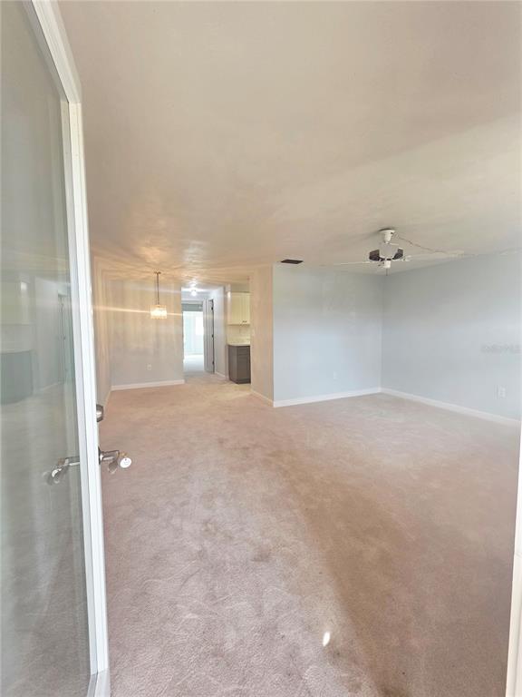 A view from a doorway into a carpeted living area with a ceiling fan — 4461 RUSTIC DRIVE, NEW PORT RICHEY, FL