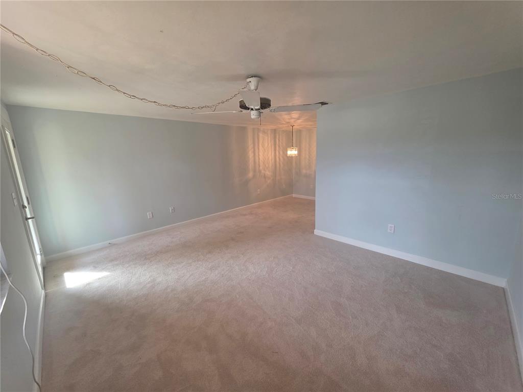 A carpeted living room features light blue walls, a ceiling fan, and a dining area — 4461 RUSTIC DRIVE, NEW PORT RICHEY, FL