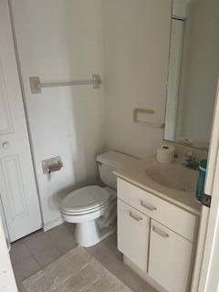 A small bathroom features a white toilet, a vanity with a sink, and a mirror — 1010 Landings Boulevard, FL 33413, FL