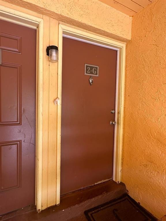 A brown apartment door labeled 2-G is set in a textured, light orange exterior wall — 4545 Treehouse Lane # G, Tamarac FL 33319, TAMARAC, FL