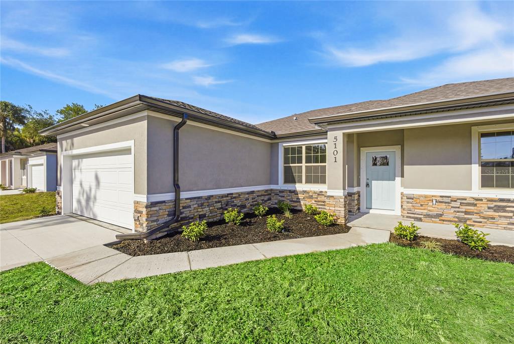 A single-story house exterior features a garage, stone veneer siding, and a light blue door — 3783 CORDOVA TERRACE, NORTH PORT, FL