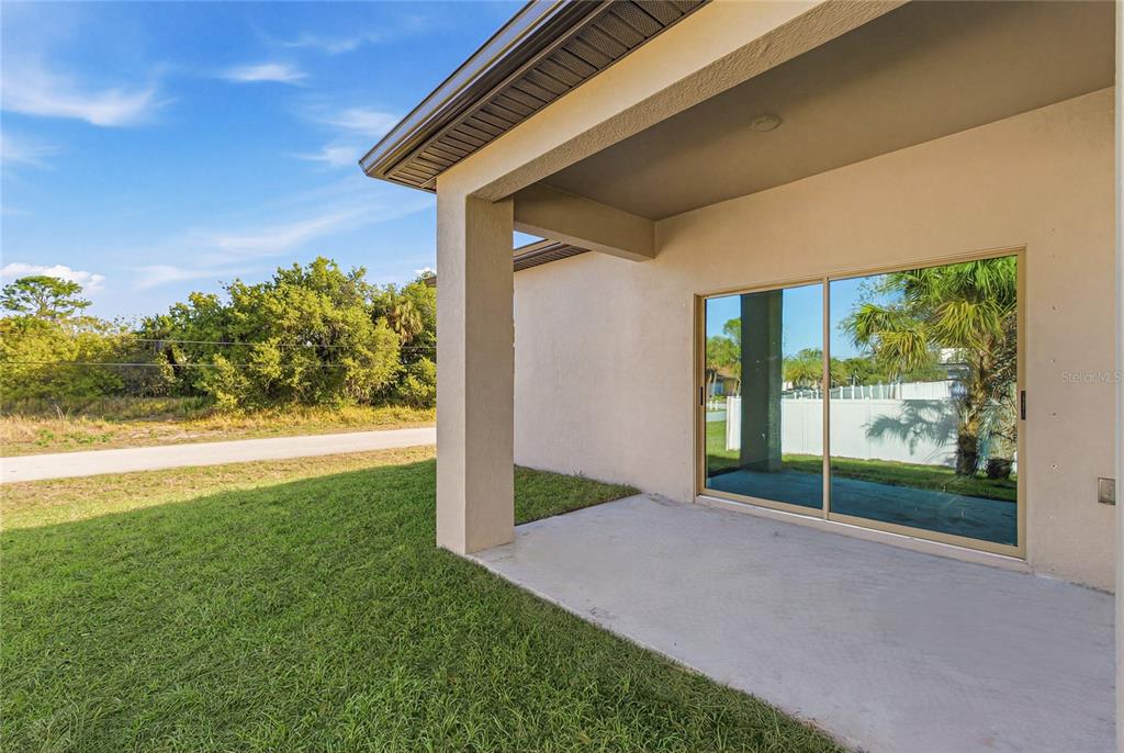 A concrete patio sits under a covered porch next to a sliding glass door — 3783 CORDOVA TERRACE, NORTH PORT, FL