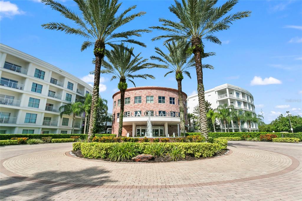 A circular brick building with a fountain and palm trees stands before two white hotels — 225 CELEBRATION PLACE UNIT 427, CELEBRATION, FL