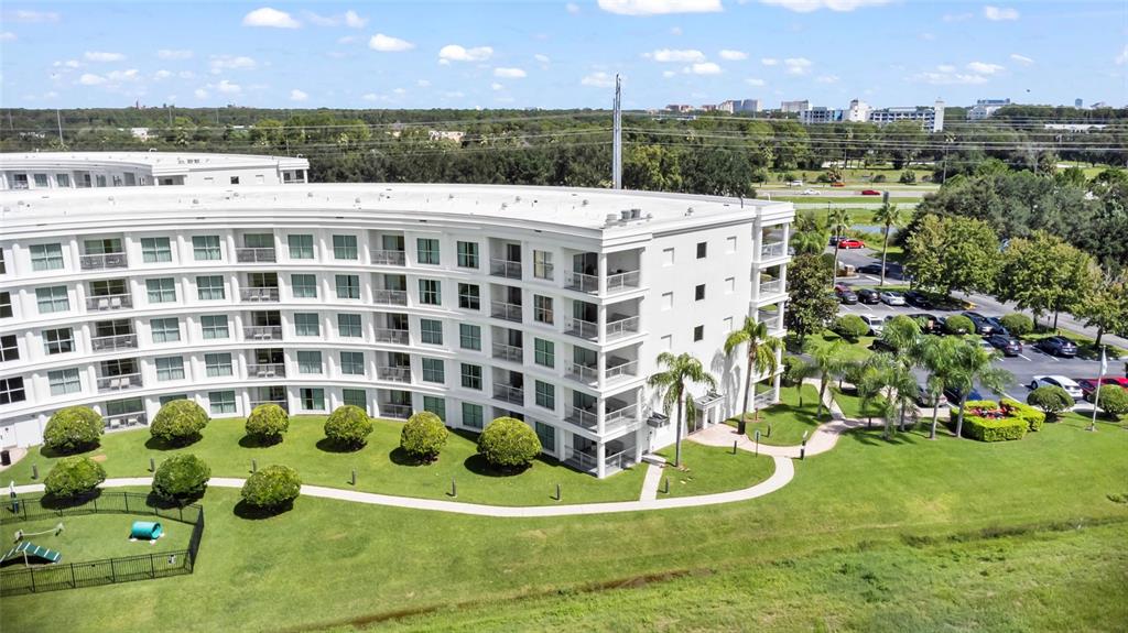 An aerial view of a curved, multi-story white apartment building with a landscaped lawn — 225 CELEBRATION PLACE UNIT 427, CELEBRATION, FL
