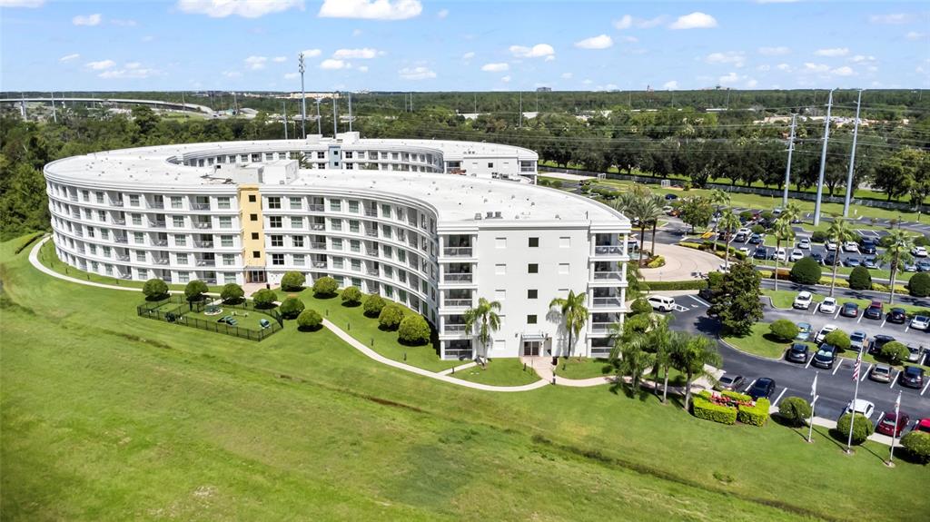 An aerial view shows a curved, multi-story apartment building with a parking lot and landscaping — 225 CELEBRATION PLACE UNIT 427, CELEBRATION, FL
