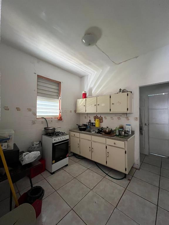 A kitchen features white cabinets, a gas stove, tiled floors, and a window with blinds — 258 H BARTOLOME DE LAS CASAS, SANTURCE, SAN JUAN, PR