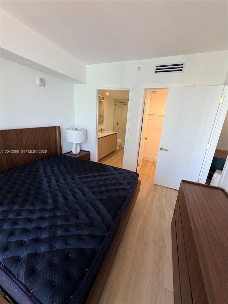 A bedroom features a dark mattress on a wooden frame, light flooring, and an attached bathroom — 90 NE 32nd St # 706, Miami FL 33137, MIAMI, FL