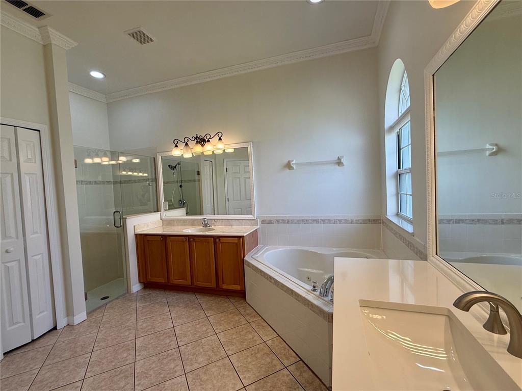 A bathroom features a glass shower, a corner soaking tub, and two separate vanity areas — 4495 HARTS COVE WAY, CLERMONT, FL