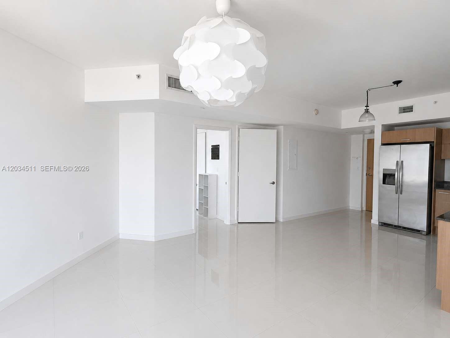An open-concept living area features white tile floors, a modern pendant light, and a kitchen — 350 S Miami Ave # 1812, Miami FL 33130, MIAMI, FL