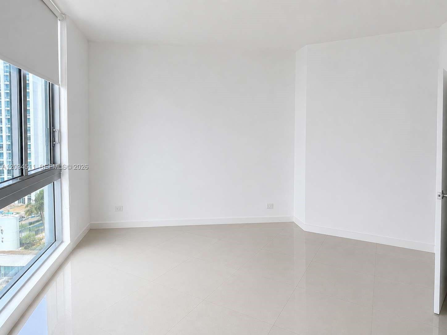 An empty room features white walls, light-colored tile flooring, and a large window with blinds — 350 S Miami Ave # 1812, Miami FL 33130, MIAMI, FL