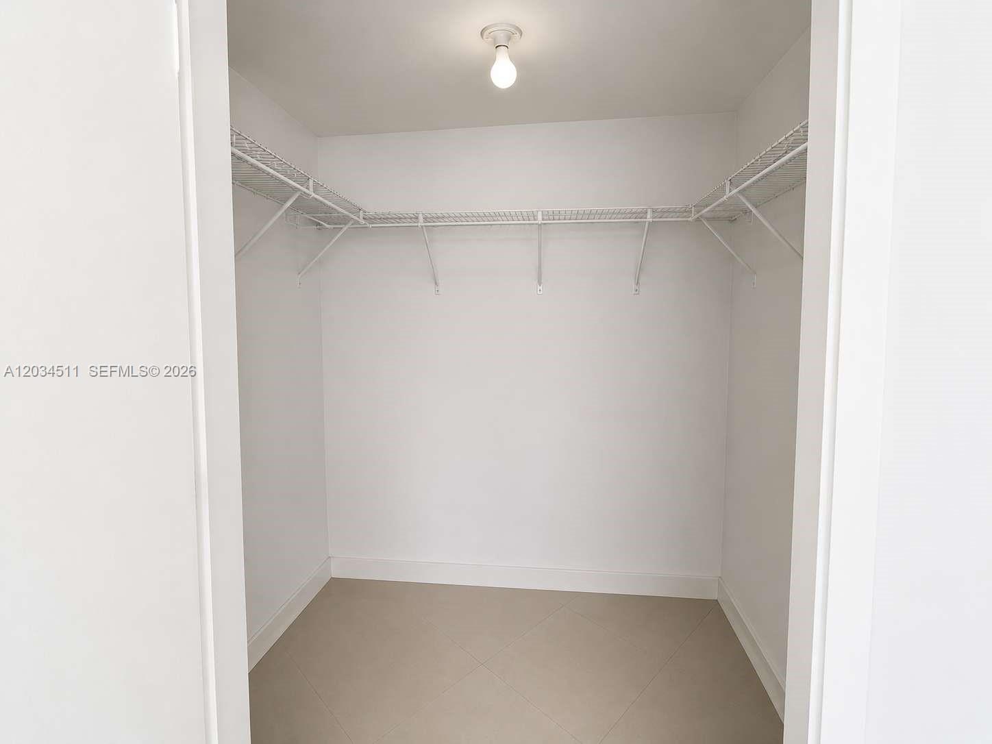 A walk-in closet features white walls, tile flooring, and white wire shelving — 350 S Miami Ave # 1812, Miami FL 33130, MIAMI, FL