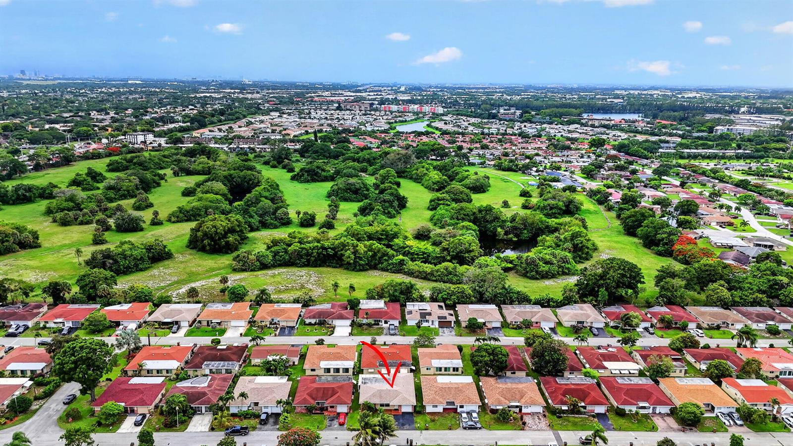 An aerial view shows a residential neighborhood with a red arrow pointing to a house — 1140 NW 49th Street, Deerfield Beach FL 33064, DEERFIELD BEACH, FL