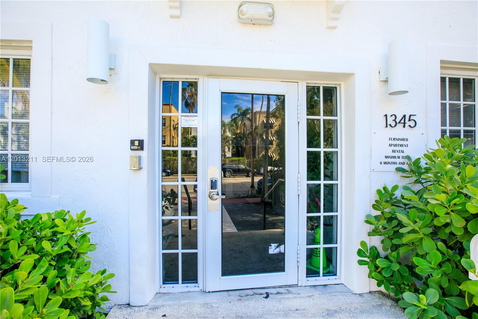 A white building entrance features a glass door with a keypad lock and side windows — 1345 Pennsylvania Ave, Miami Beach FL 33139, MIAMI BEACH, FL