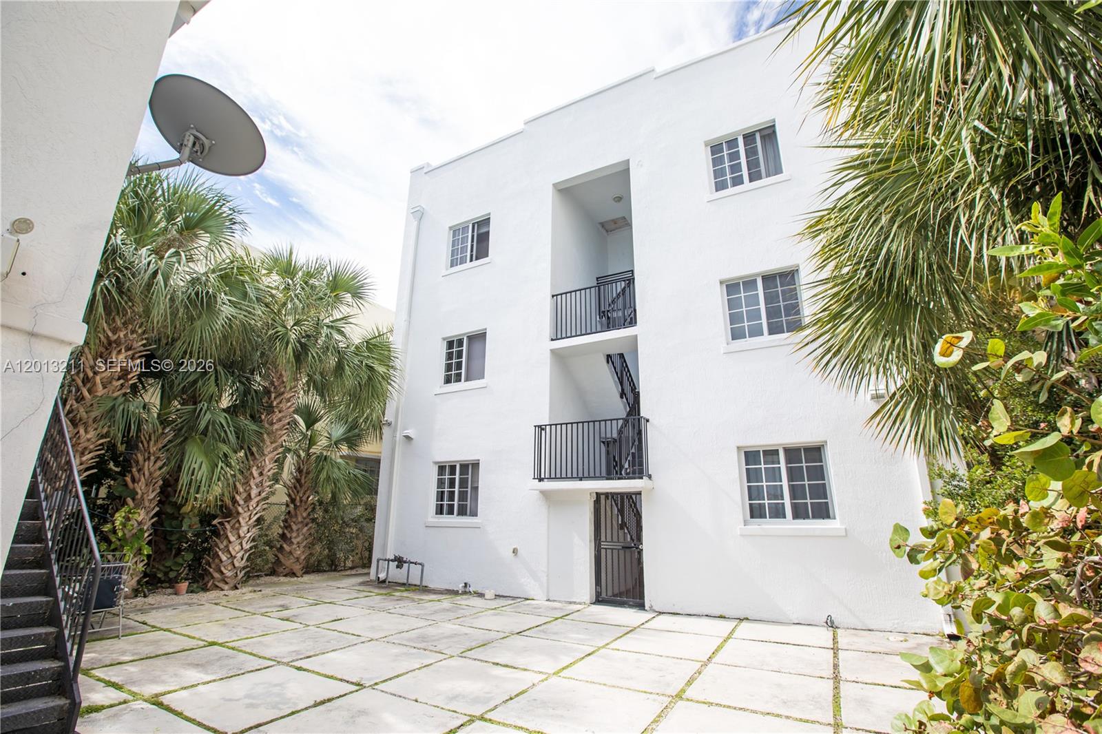 A three-story white apartment building features exterior staircases and a paved patio area — 1345 Pennsylvania Ave, Miami Beach FL 33139, MIAMI BEACH, FL