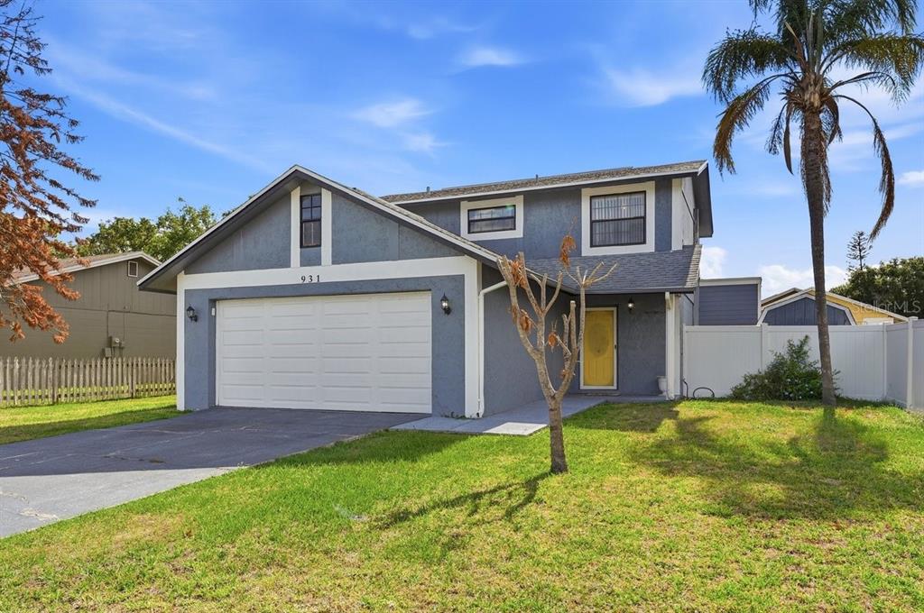 A two-story blue house with a white garage door and a yellow front door — 931 WHISPER LAKE DRIVE, WINTER HAVEN, FL