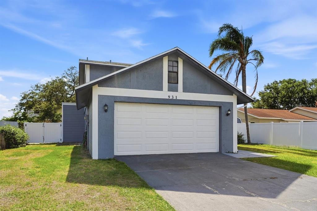 A blue house with a white garage door and a palm tree in the yard — 931 WHISPER LAKE DRIVE, WINTER HAVEN, FL