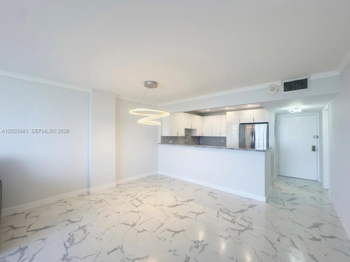 An open-concept living area features white marble-patterned tile floors and a kitchen with white cabinetry — 3800 S Ocean Dr # 802, Hollywood FL 33019, HOLLYWOOD, FL