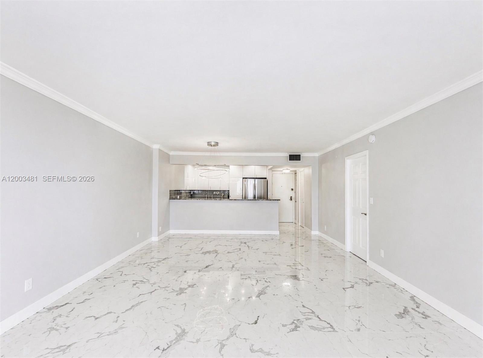 An open-concept living area features white walls, crown molding, and polished marble-look tile flooring — 3800 S Ocean Dr # 802, Hollywood FL 33019, HOLLYWOOD, FL