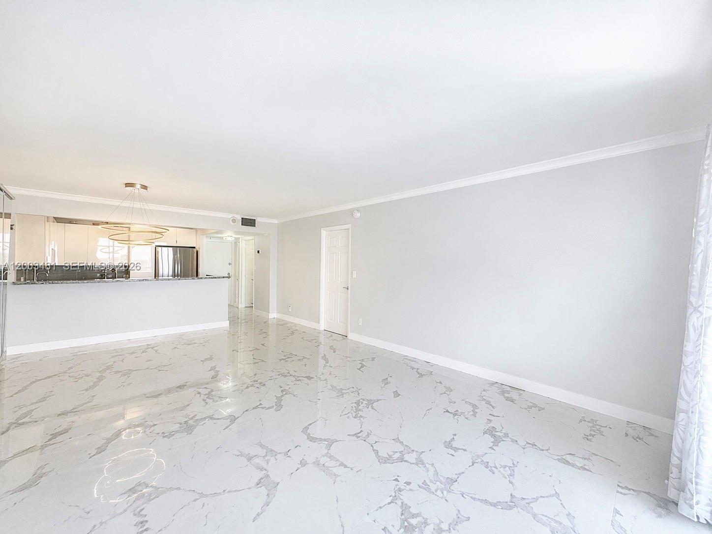 A spacious room features white marble-patterned tile flooring, light gray walls, and an open kitchen — 3800 S Ocean Dr # 802, Hollywood FL 33019, HOLLYWOOD, FL