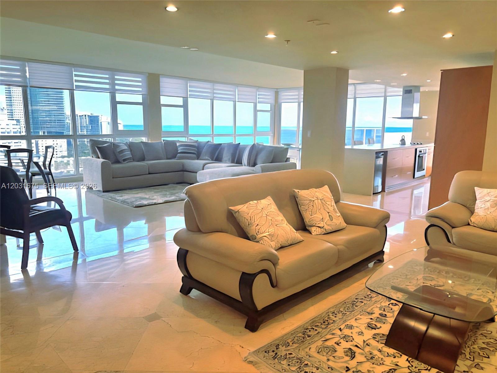 A spacious living room features light-colored sofas, a glass coffee table, and floor-to-ceiling windows — 100 Lincoln Rd, Miami Beach FL 33139, MIAMI BEACH, FL