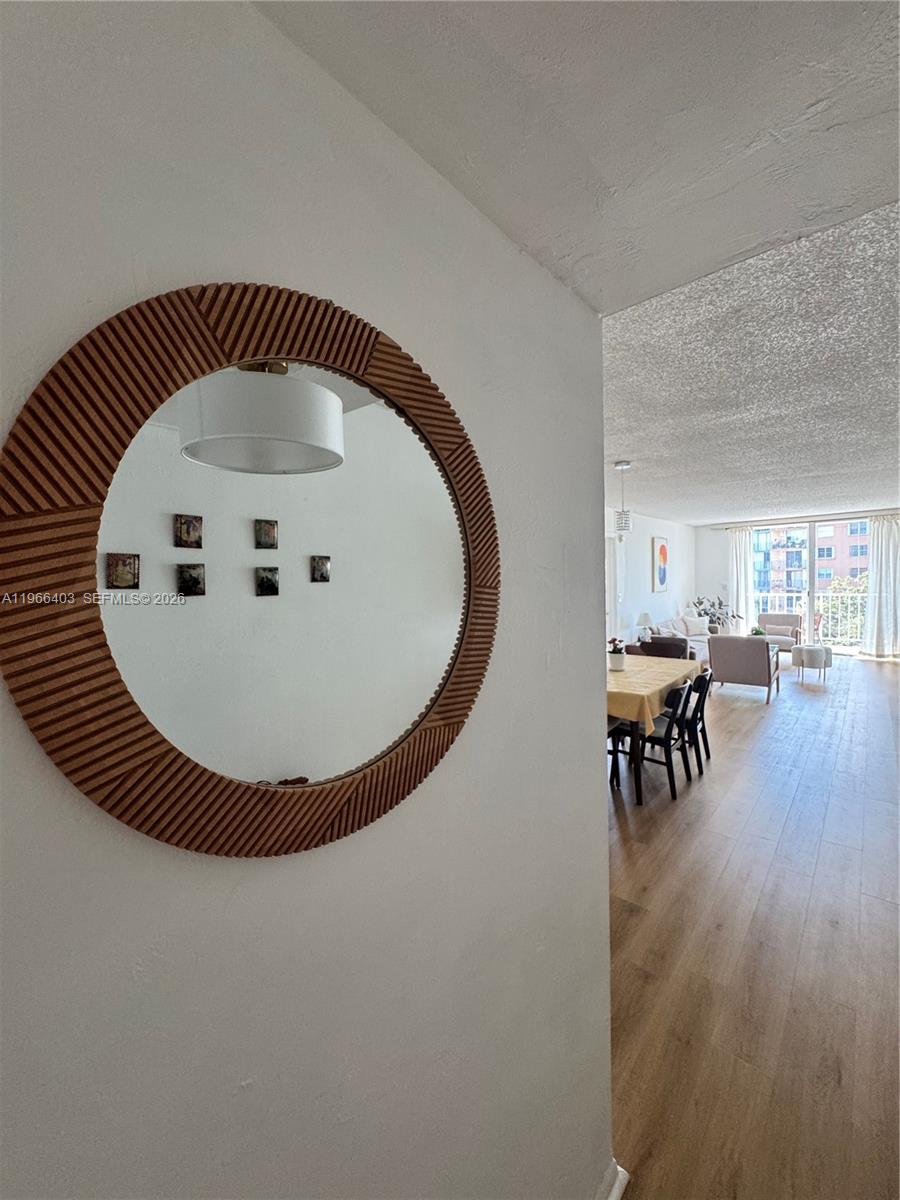 A round, textured mirror hangs on a wall overlooking a dining and living area — 1470 NE 125th Ter # 407, North Miami FL 33161, NORTH MIAMI, FL