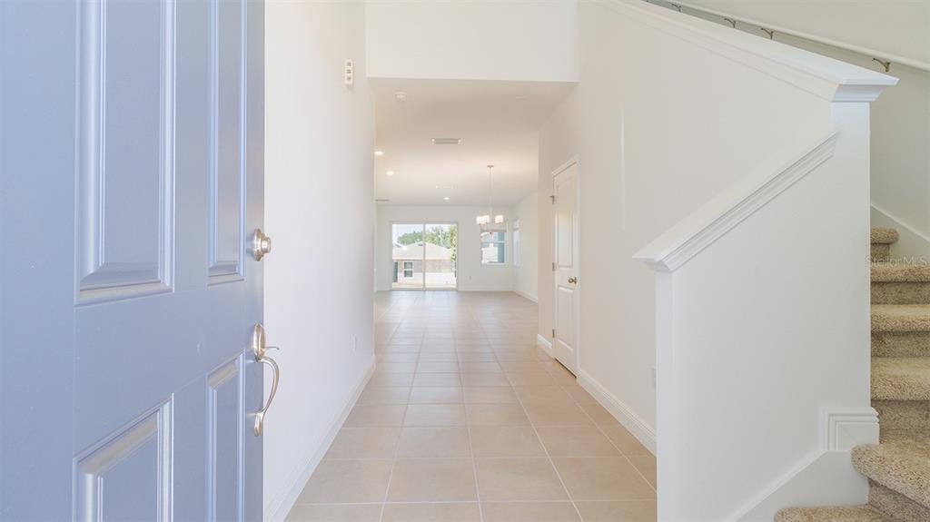 A foyer with tile flooring leads to an open living area and a carpeted staircase — 2144 SUNSHINE PEAK DRIVE, MINNEOLA, FL