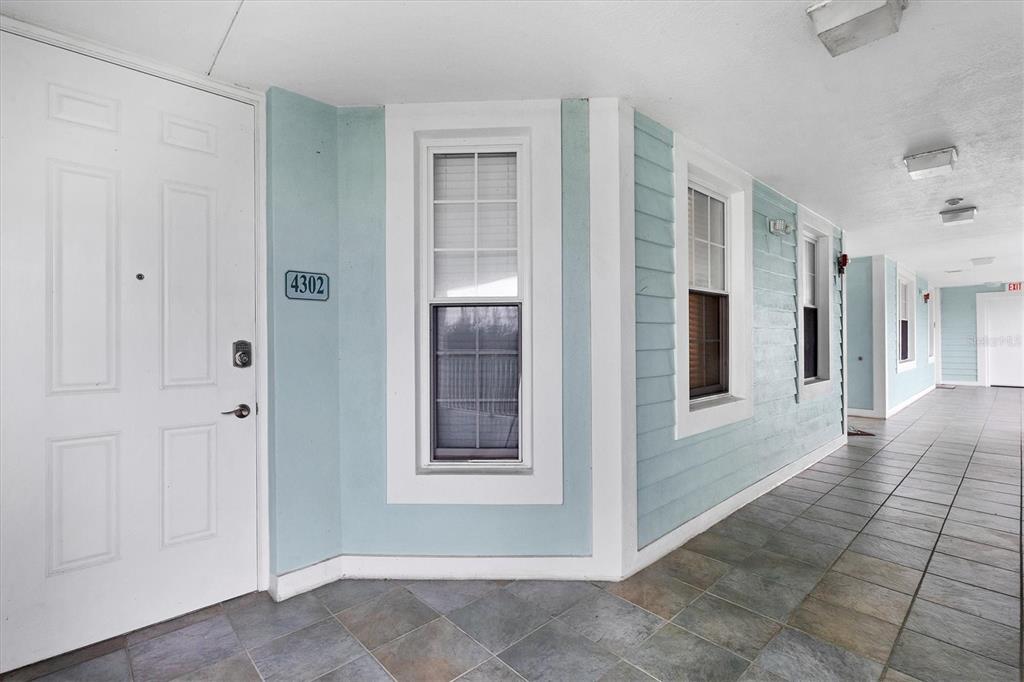 A white door with number 4302 sits beside a window on a tiled outdoor walkway — 5117 MELBOURNE STREET UNIT B4302, PORT CHARLOTTE, FL