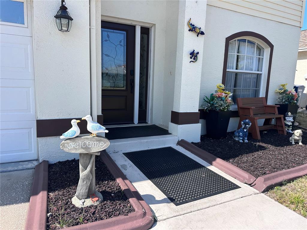 The exterior entrance features a dark door, a welcome sign with seagulls, and decorative figurines — 10632 LAKE VISTA DRIVE, SEMINOLE, FL