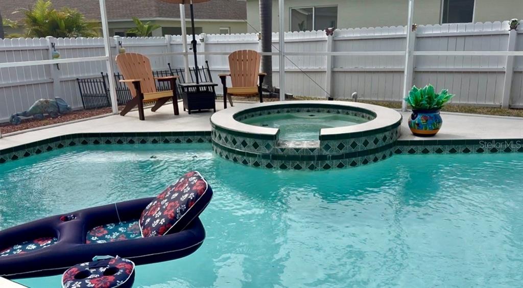 A swimming pool with an integrated spa sits on a patio enclosed by a screen — 10632 LAKE VISTA DRIVE, SEMINOLE, FL