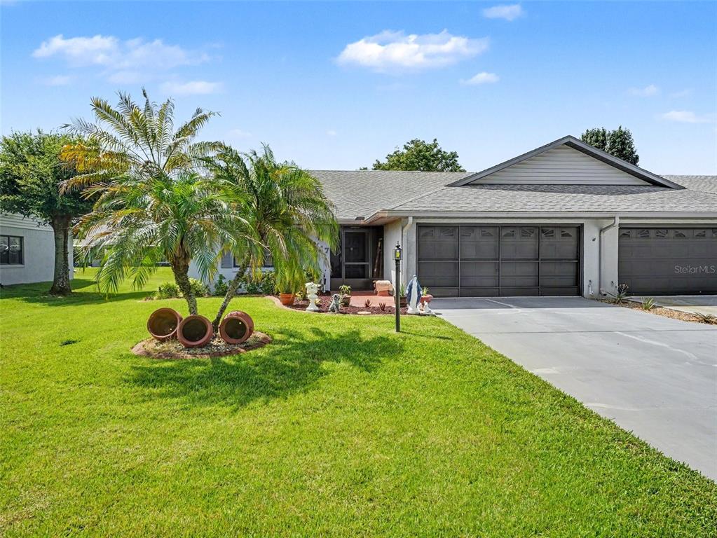 A single-story house with a palm tree, a concrete driveway, and a two-car garage — 1717 W ORANGEWOOD LANE UNIT 4, AVON PARK, FL