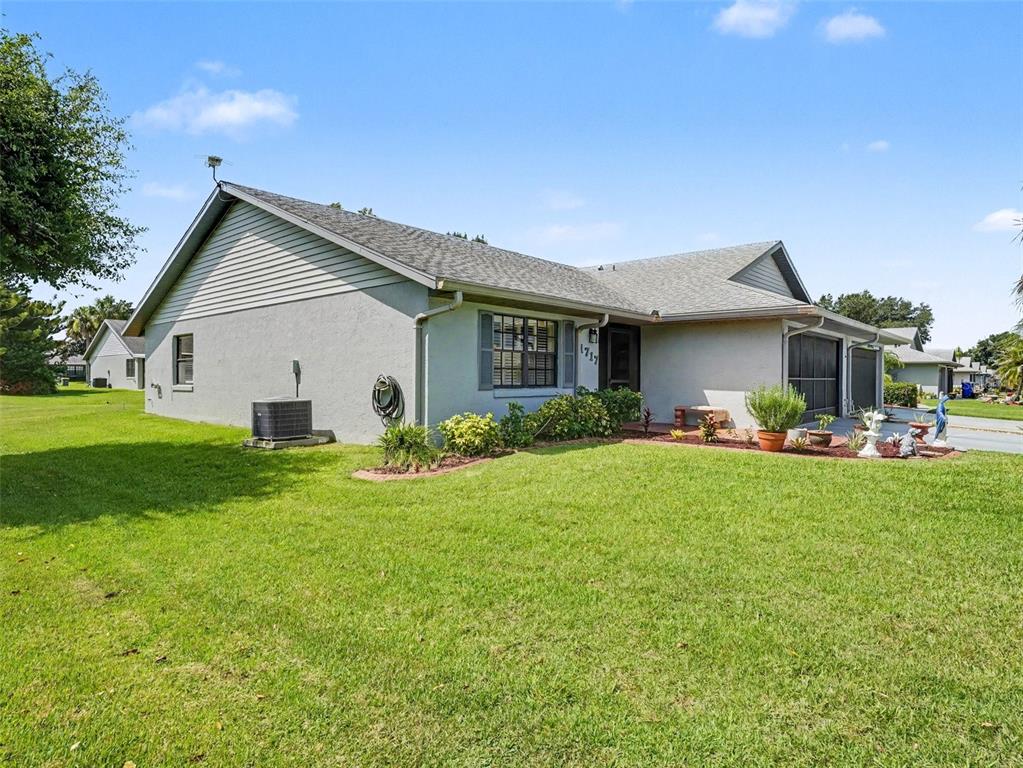 A single-story house with a gray stucco exterior, a shingled roof, and a front lawn — 1717 W ORANGEWOOD LANE UNIT 4, AVON PARK, FL