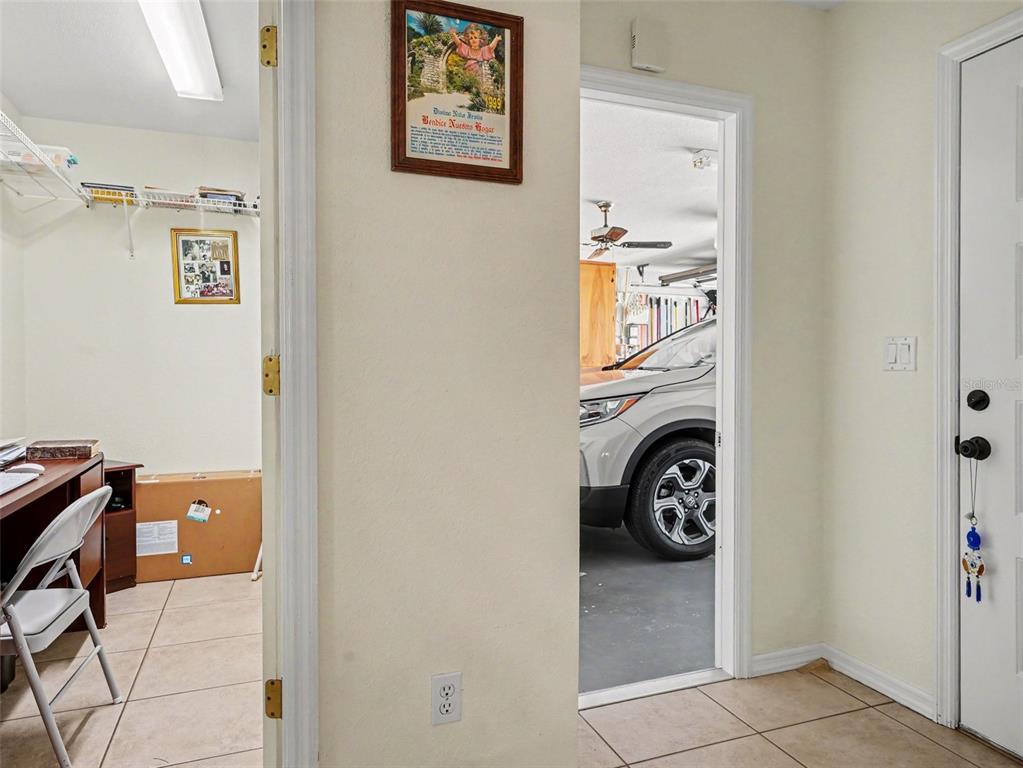 A view from a tiled hallway into a home office and an attached garage — 1717 W ORANGEWOOD LANE UNIT 4, AVON PARK, FL