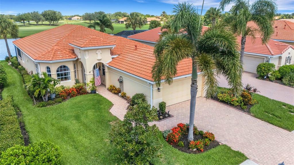 An aerial view of a single-story house with a tile roof, driveway, and palm trees — 185 SAVONA WAY, NOKOMIS, FL