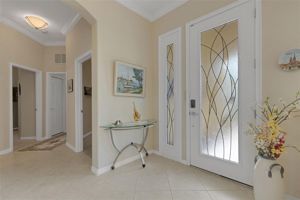 An entryway features tile flooring, a glass-paneled front door, and a glass console table — 185 SAVONA WAY, NOKOMIS, FL