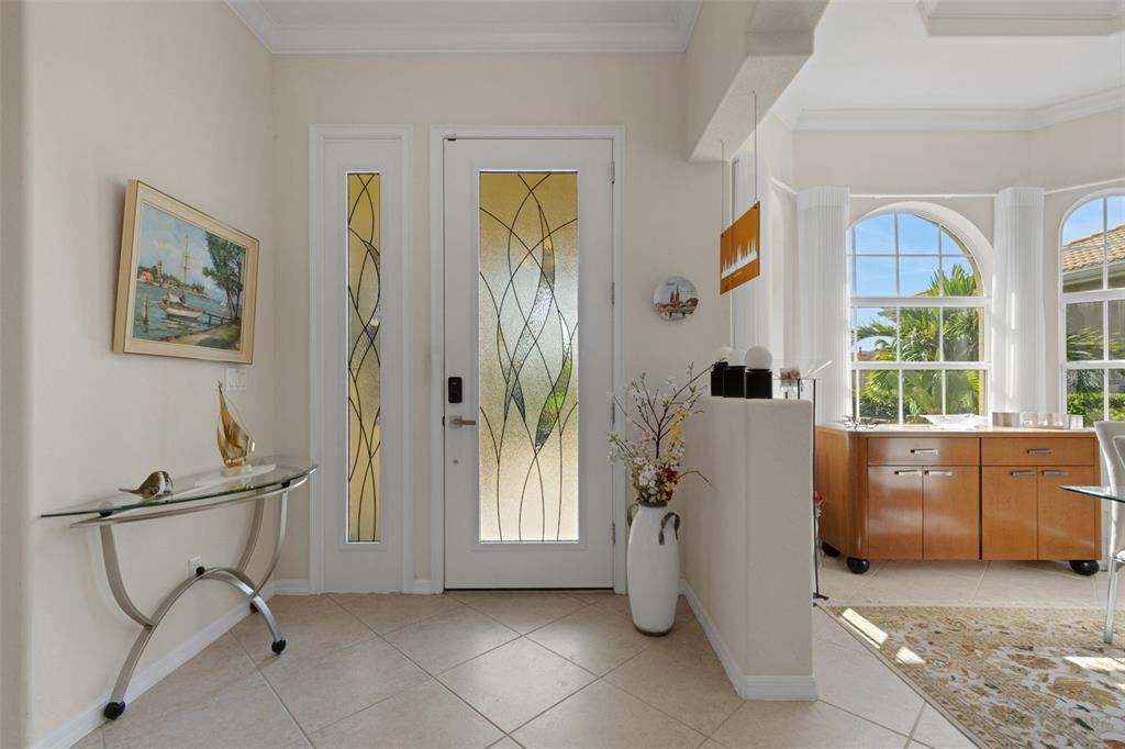 An entryway features a glass-paneled front door, tile flooring, a console table, and a half wall — 185 SAVONA WAY, NOKOMIS, FL