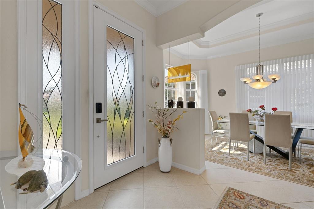 An entryway with a glass-paneled door leads into a dining room with a chandelier — 185 SAVONA WAY, NOKOMIS, FL
