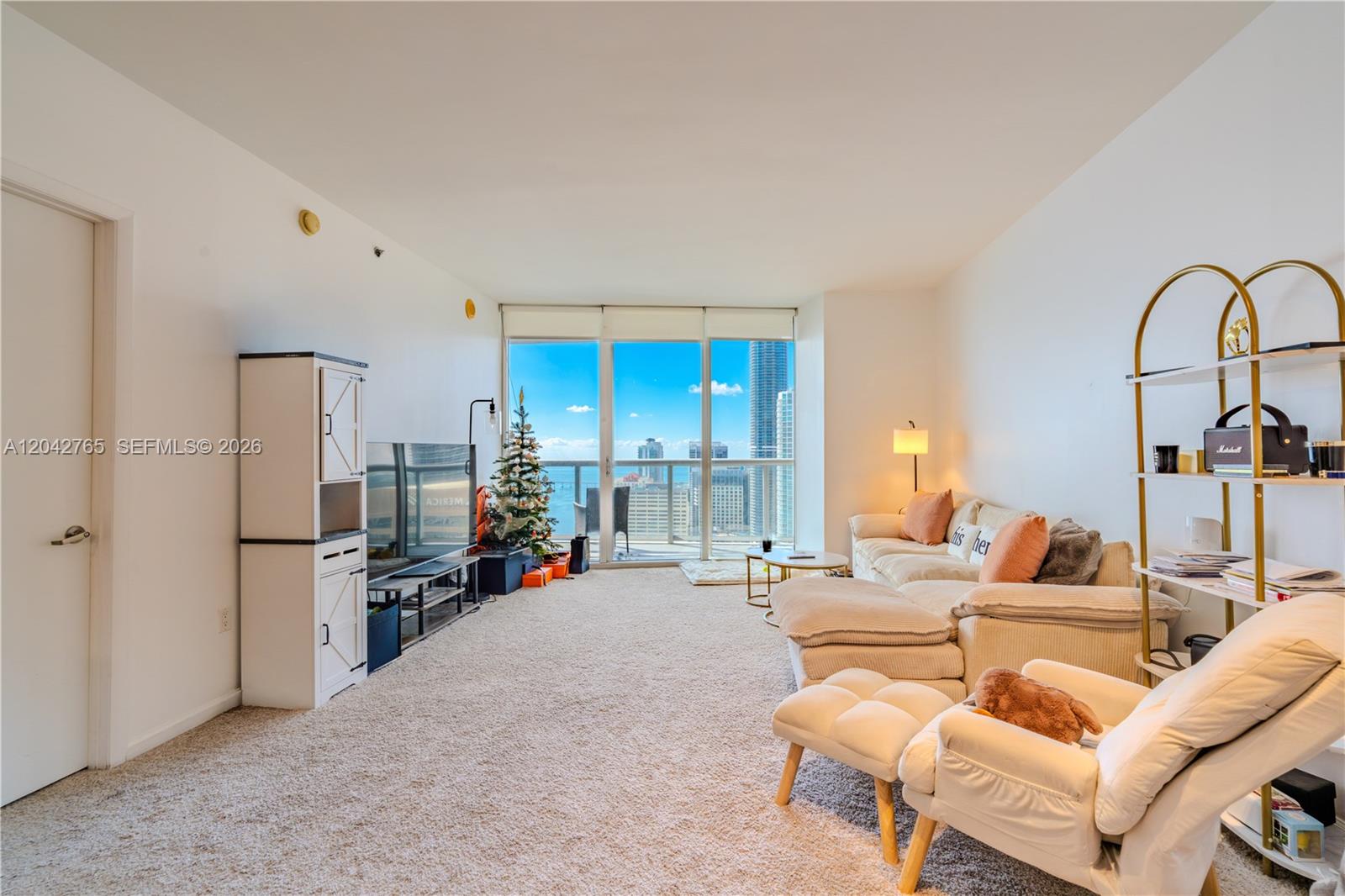A living room with beige carpet, a sectional sofa, and floor-to-ceiling windows overlooking a city — 495 Brickell Ave # 4609, Miami FL 33131, MIAMI, FL