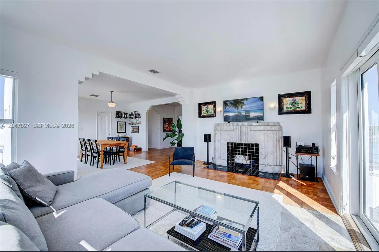 A living room with a fireplace, television, glass coffee table, and adjacent dining area — 4035 N Meridian Ave PH, Miami Beach FL 33140, MIAMI BEACH, FL