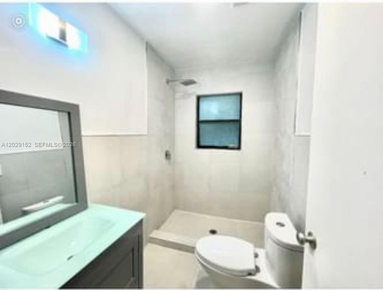 A bathroom features a walk-in shower, a vanity with a mirror, and a toilet — 1220 S 29th Ave, Hollywood FL 33020, HOLLYWOOD, FL