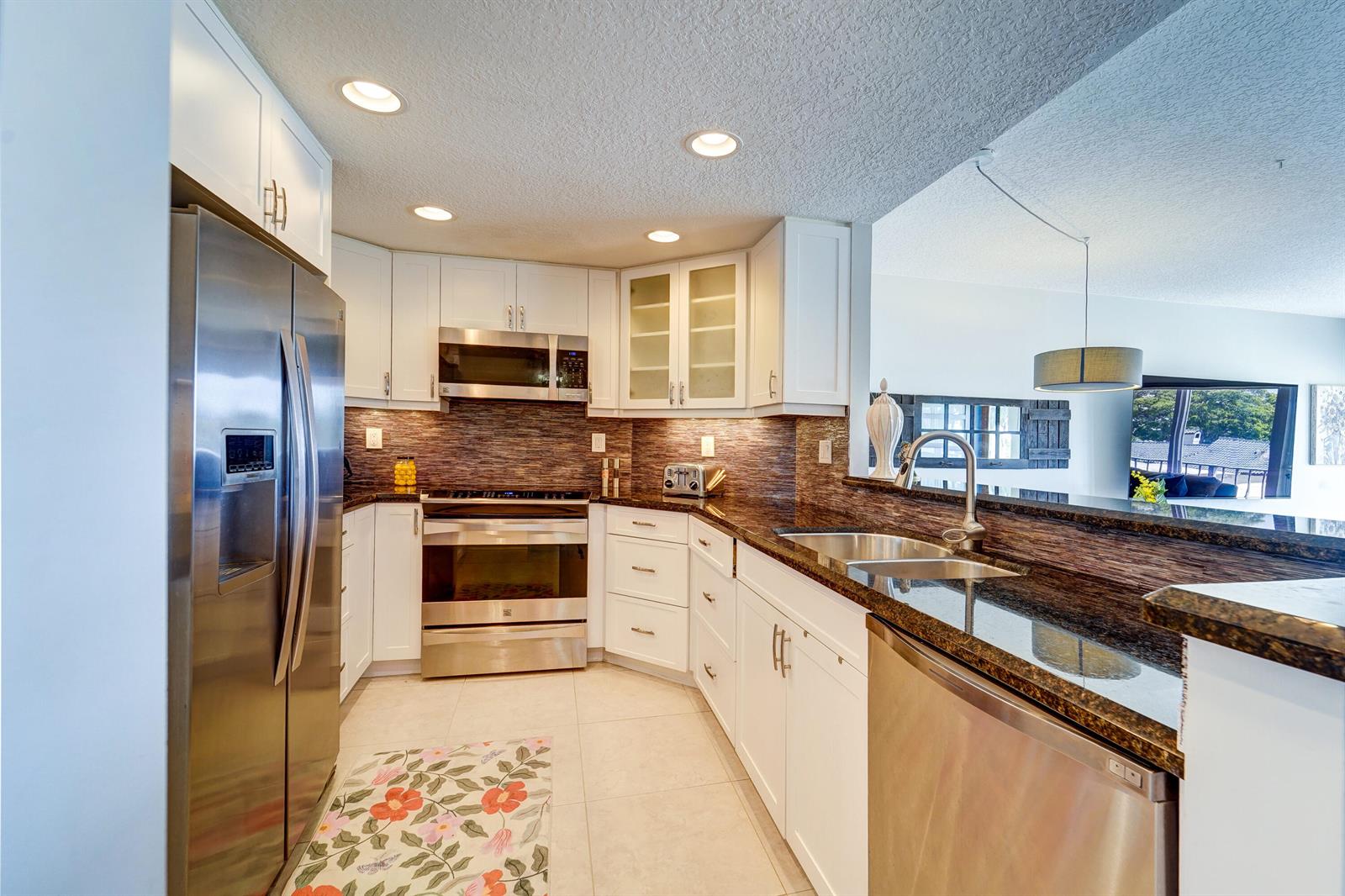 A kitchen features white cabinets, stainless steel appliances, and dark granite countertops — 2500 E Las Olas Boulevard # 403, Fort Lauderdale FL 33301, FORT LAUDERDALE, FL