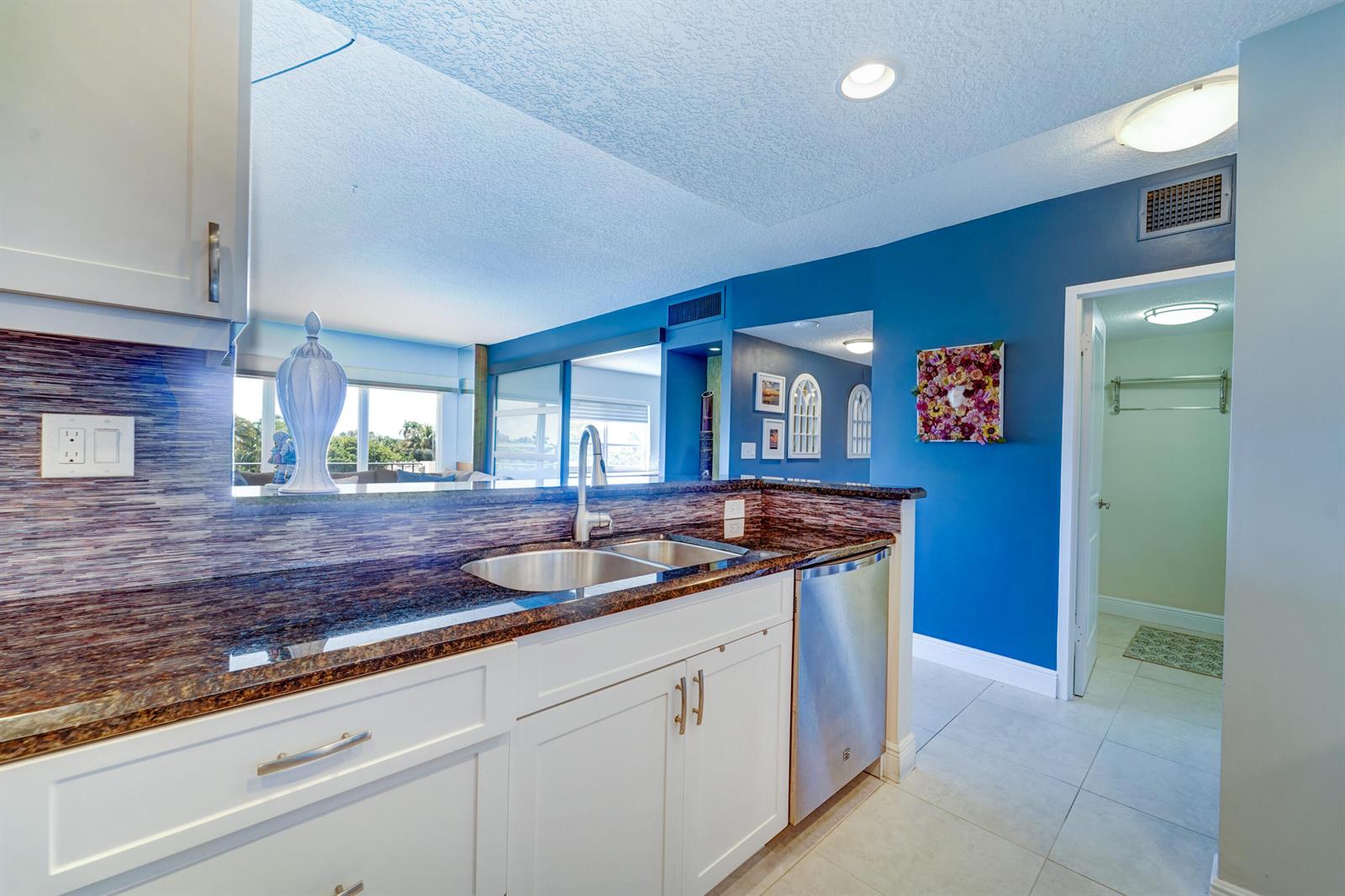 A kitchen features white cabinets, dark granite countertops, a stainless steel dishwasher, and blue walls — 2500 E Las Olas Boulevard # 403, Fort Lauderdale FL 33301, FORT LAUDERDALE, FL