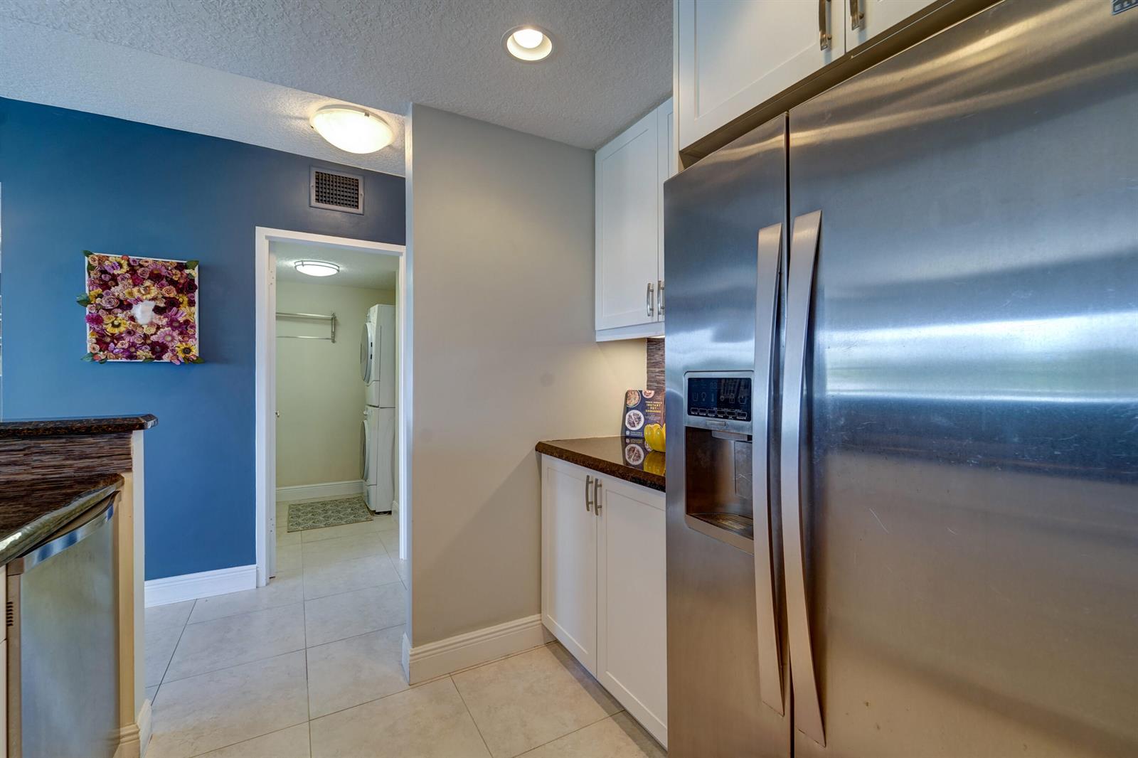 A kitchen area features white cabinets, stainless steel appliances, and a doorway leading to laundry — 2500 E Las Olas Boulevard # 403, Fort Lauderdale FL 33301, FORT LAUDERDALE, FL