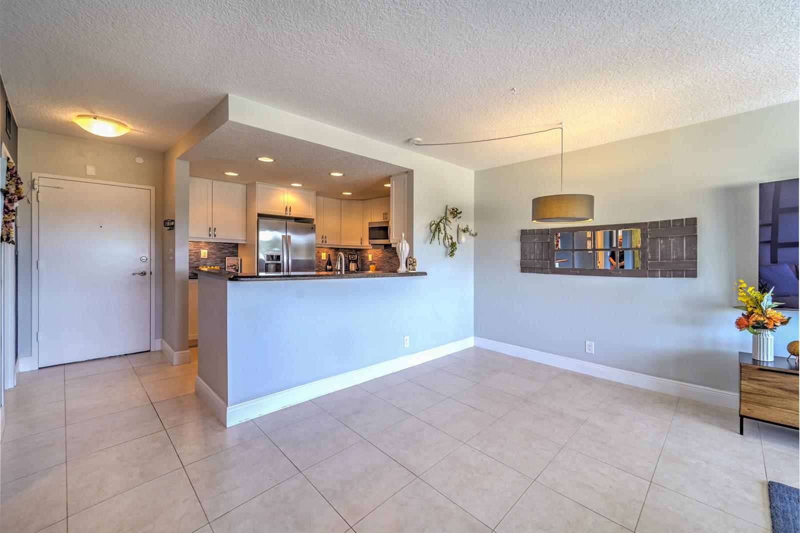 A kitchen with white cabinets and a breakfast bar overlooks an open-concept dining area — 2500 E Las Olas Boulevard # 403, Fort Lauderdale FL 33301, FORT LAUDERDALE, FL