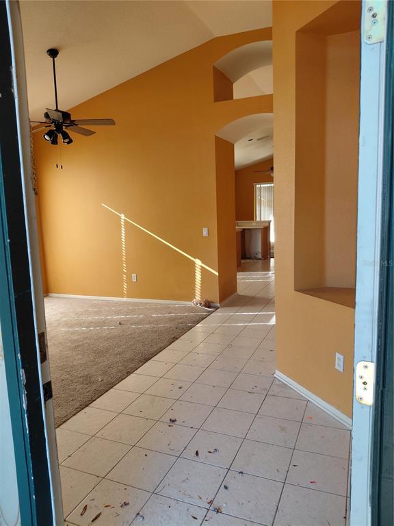A view from a doorway into a living room with carpet, tile flooring, and yellow walls — 18124 ANTIETAM COURT, TAMPA, FL